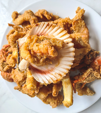 Seafood crackling served with seashell. Chicharrón mixto de pescado y mariscos. servido con yuca y concha.