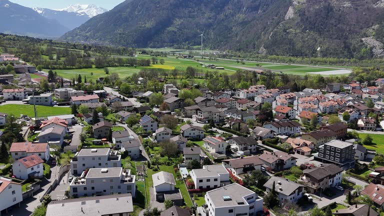 Swiss Homes and Houses with solar panels on roof. Sunny bright day in Switzerland. Trimmis Town a small swiss city. Modern new development buildings. Aerial orbit wide shot.