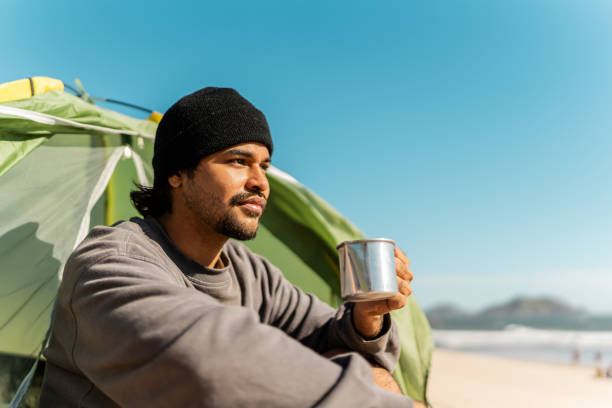 istock Young man contemplating and drinking coffe on the beach 2149296926