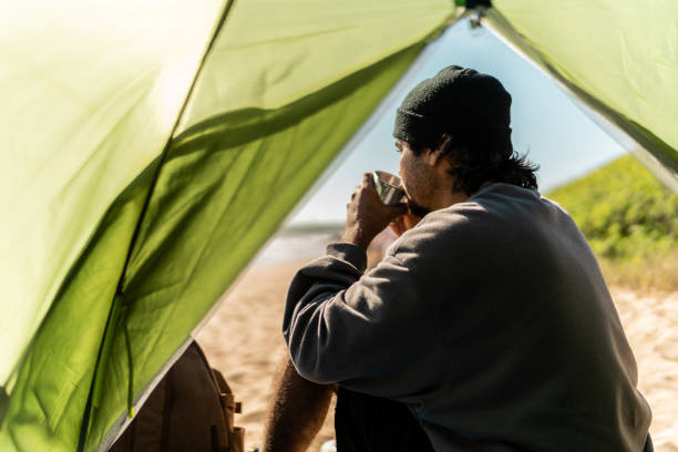 istock Young man contemplating and drinking coffee on the beach 2149299300