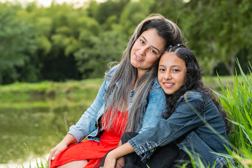 close-up of a young Latina mother and her daughter looking on and smiling happily