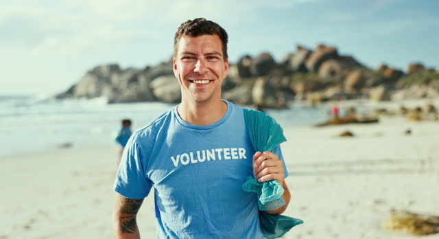 Portrait, volunteer and smile of man at beach for cleaning trash, recycling and environment conservation. Face, garbage bag and happy person at ocean for community service, ecology and charity at sea