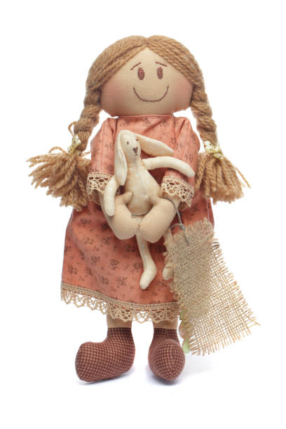 Cute handmade doll with easter bunny in her hand on white background