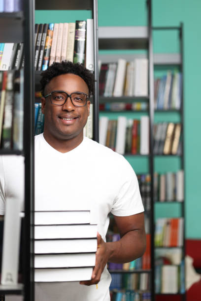 istock Positive african librarian putting new interesting books on shelves 2149301275