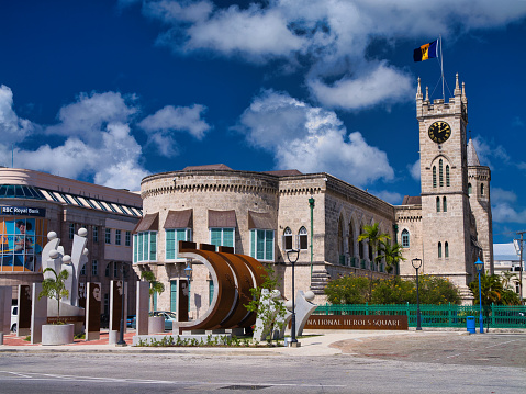 Barbados - Jan 28 2024: At the heart of Heroes Square in Bridgetown, Barbados, the Monument to the Barbadian Family. In the background the Parliament Buildings, the seat of the Parliament of Barbados.