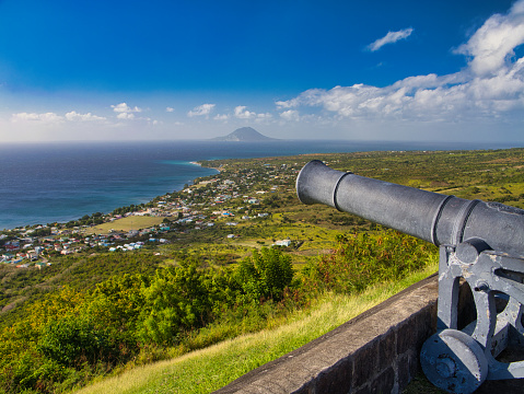 St Kitts - Jan 25 2024: A cannon on a battlement at the Brimstone Hill Fortress National Park on St Kitts in the Caribbean. Taken on a sunny day with a blue sky and view of the coastline.