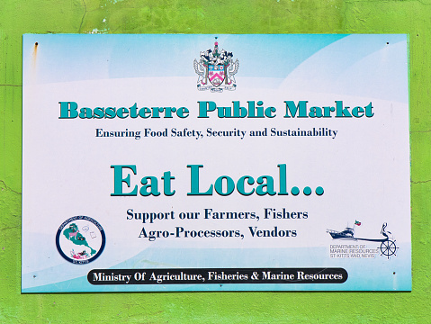 Basseterre, St Kitts - Jan 25 2024: A sign at the Basseterre Public Market encourages people to support local producers and sellers of food and produce.