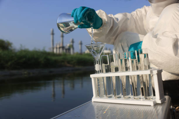 environmentalist use a chemical flask to collect the  samples of toxic water for testing and check with quality of water from industrial