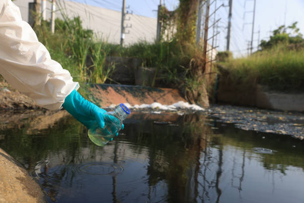 istock Close-up scientist or environment engineer's hand with a chemical protective suit and PPE collect a sample of toxic water from an industrial waterway 2149301677
