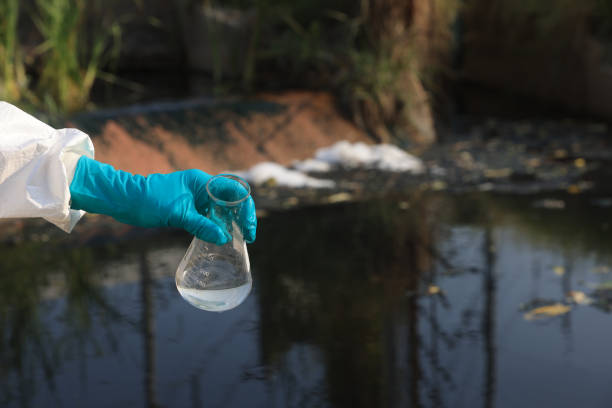 istock Close-up scientist or environment engineer's hand with a chemical protective suit and PPE collect a sample of toxic water from an industrial waterway 2149301683