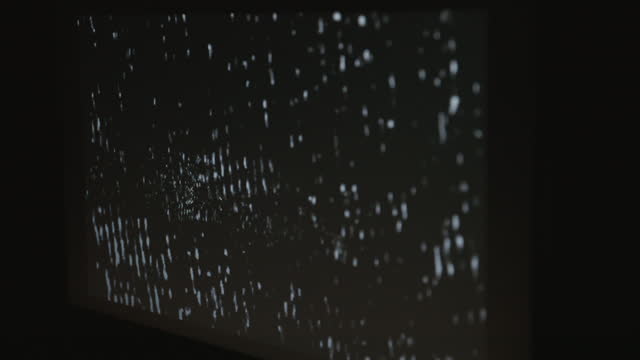 A single computer monitor screen flashing a strobing static noise pattern in a dark room.