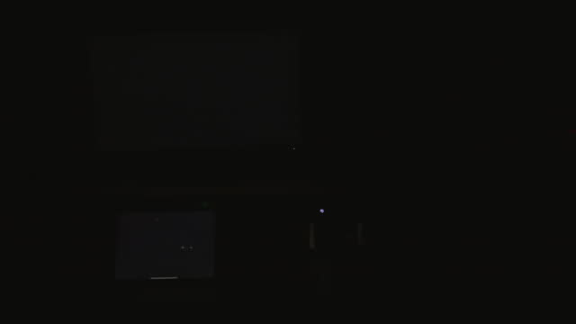 Four digital computer device screens flashing a strobing static noise pattern in a dark room.