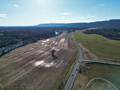 view of small country road in new paltz (shawangunk mountain ridge in the background) cars driving over bridge down highway over river (hudson valley new york) drone photo aerial view from above