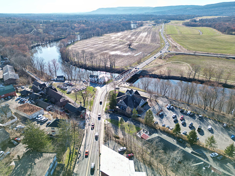view of small country road in new paltz (shawangunk mountain ridge in the background) cars driving over bridge down highway over river (hudson valley new york) drone photo aerial view from above
