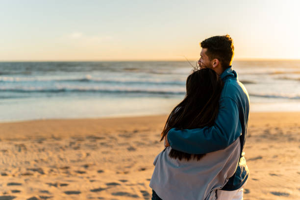 istock Couple embraced looking at view on beach 2149306753