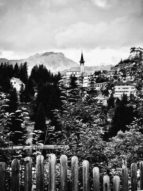 An outside view of a Swiss village taken with a view of the village, church spire, and snow capped mountains