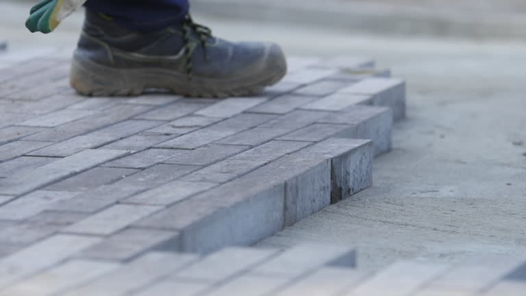 Worker in protective gloves paves pathway with paving tiles