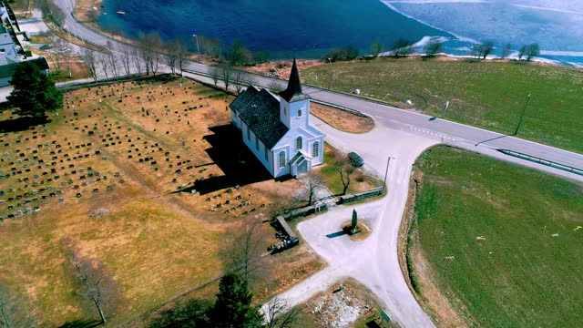 Stunning drone view of a Nordic church standing amidst a sea of lush green landscapes