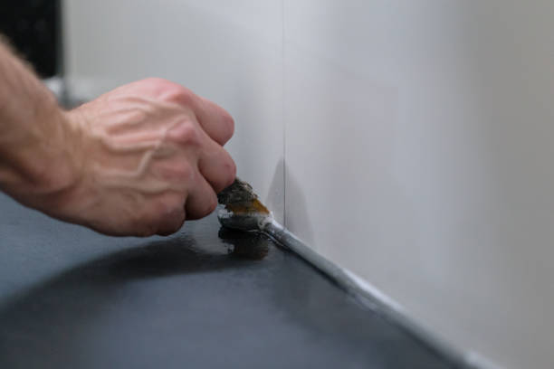 istock Hand of a tiler removing superfluous putty in a batthroom 2149310520