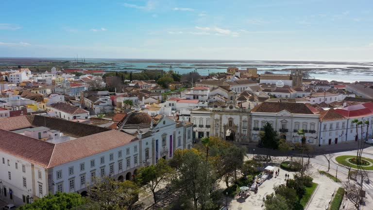 Portuguese oceanfront city of Faro with ancient architecture, filmed with a drone. Arco de Villa and Largo de Se. Ria Formosa and boat harbor in background.