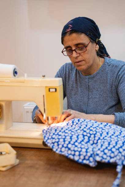 istock A middle-aged woman in a headscarf sews on a sewing machine, in a home environment 2149312821
