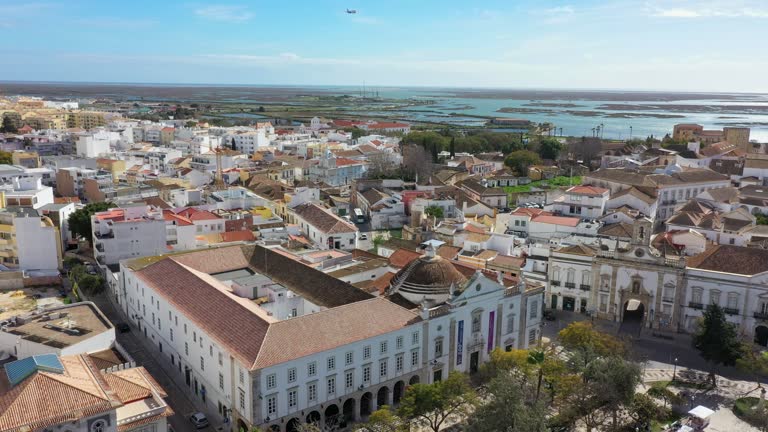 Traditional Portuguese town of Faro on oceanfront with old architecture, filmed by drone. Arco de villa and largo de se. Ria formosa in background.