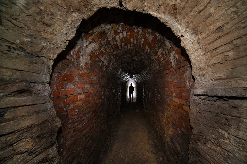 Sewer worker in underground sewer tunnel.