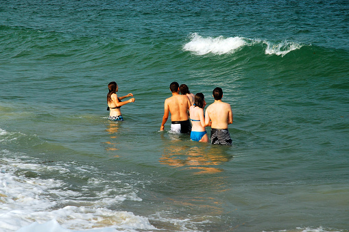 Hampton Beach, NH, USA July 15 A group of friends brace themselves for the next ocean wave on a summer vacation day at the coast in Hampton Beach, New Hampshire