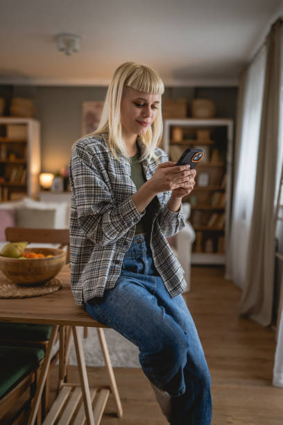 istock Young woman text message and browse internet on mobile phone at home 2149318610