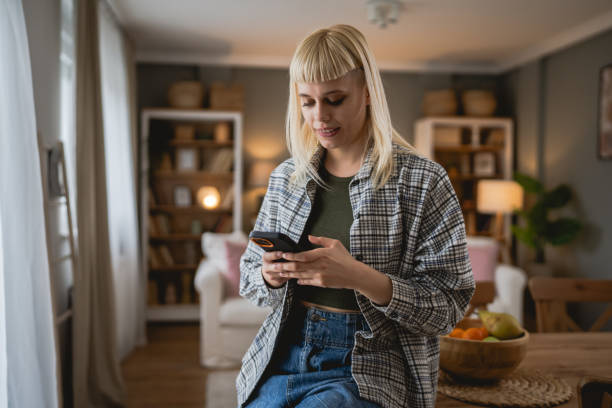 istock Young woman text message and browse internet on mobile phone at home 2149318648