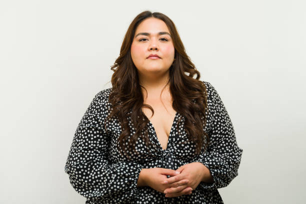 Plus-size woman stands confidently in a stylish dress against a white studio backdrop