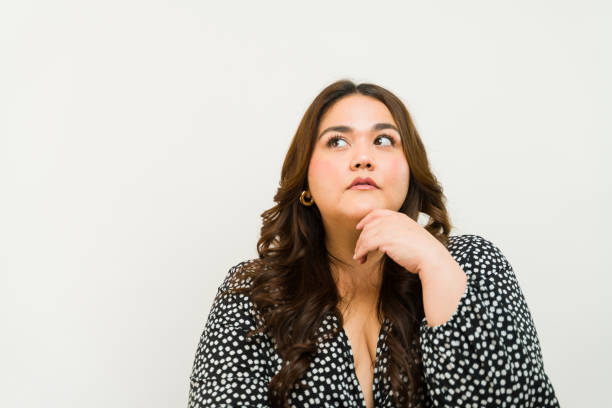 Self-assured plus-size woman with a thoughtful expression on a simple backdrop