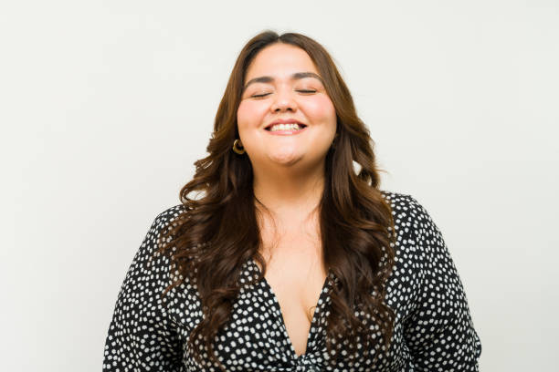 Cheerful plus-size woman with an enchanting smile modeling a dress against a bright studio backdrop