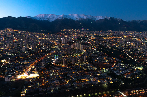 The city of Tehran the capital of Iran at night with  snowcapped mountains behind