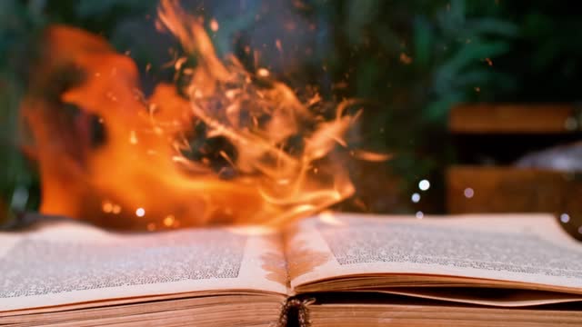 The book is engulfed in flames, descending onto a flattened surface, portraying the concept of devastation and ruin. Slow motion scene.