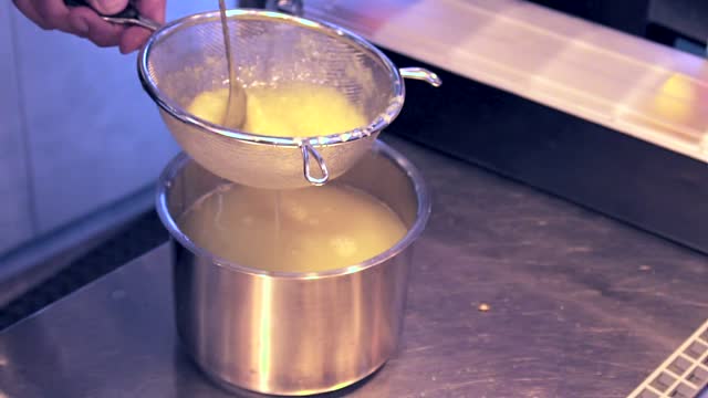 Side view, close up shot on hand's of bartender stirring lemon juice in a colander.Slow motion 100fps