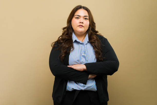 istock Professional plus-size woman in smart attire with arms crossed in a studio setting 2149322496