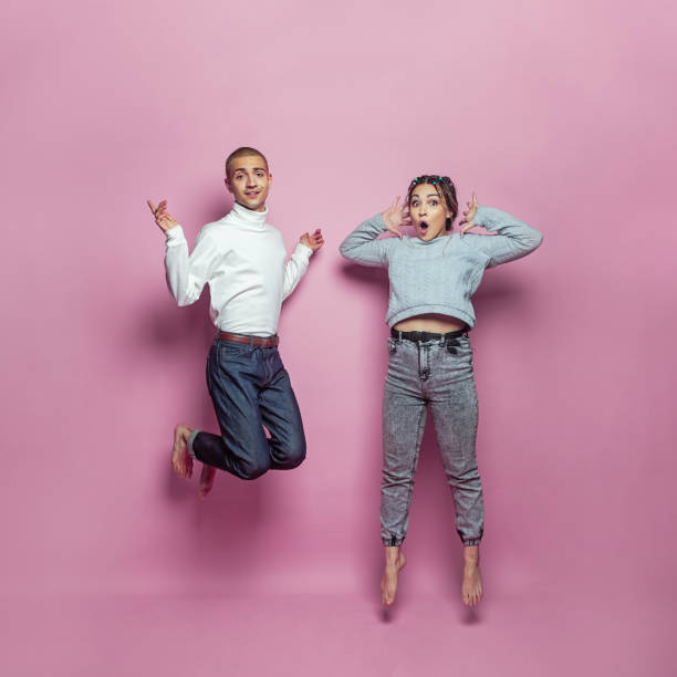 two people jumping up and smiling on pink background
