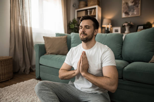 Tranquil man doing yoga and meditating at home.