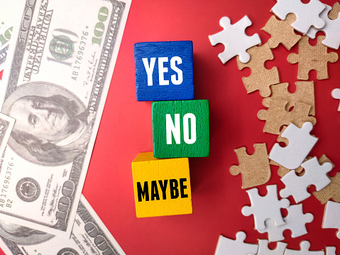 Banknotes and puzzle with the word YES NO MAYBE on red background. Business concept.