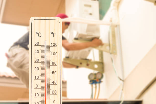 istock Thermometer with blurred technician install new air conditioner background, Hot temperature 2149336278