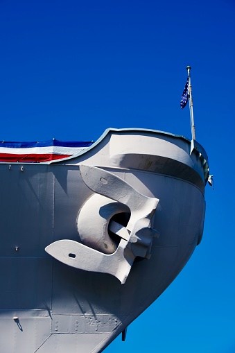 Norfolk, Virginia, USA - April 14, 2024: A massive anchor and the bow of the USS Wisconsin battleship seen against a blue sky on a sunny afternoon.