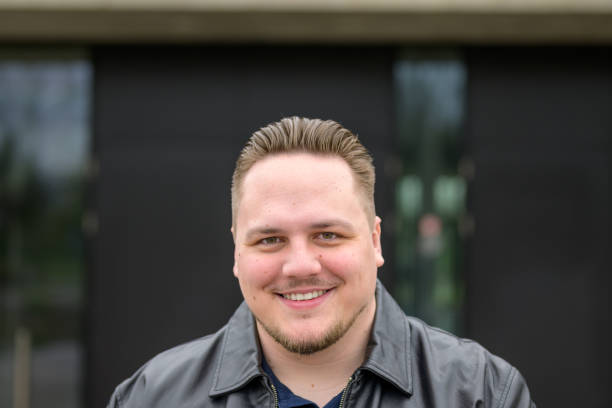 istock Young man in a black leather jacket and slicked back hair looking friendly to camera 2149340471