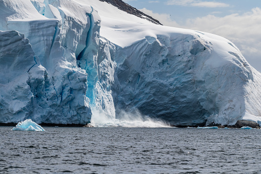 Telephoto of a giant chunk of ice calving off an ice sheet. Graham Passage, near Charlotte Bay, on the Antarctic Peninsula
