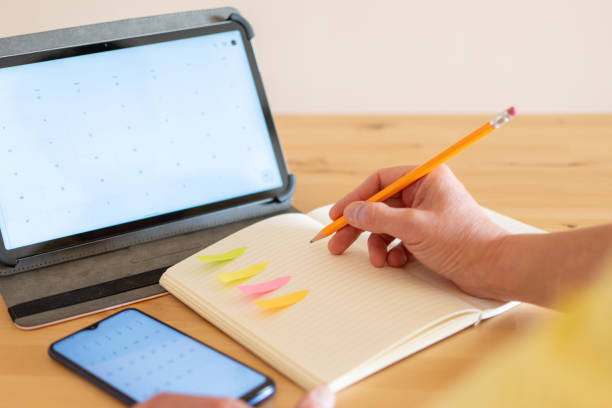 Unrecognizable Person Organizing And Planning The Agenda, Uses Digital Tablet, Smartphone And A Notebook. Concept Of Organization And Planning.