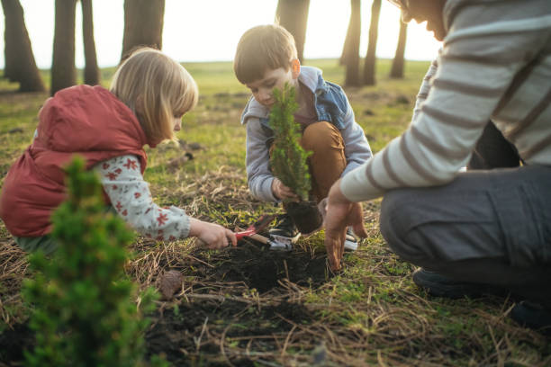 istock Father and children planting trees outdoors in springtime 2149349796