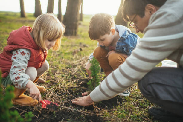 istock Father and children planting trees outdoors in springtime 2149349830