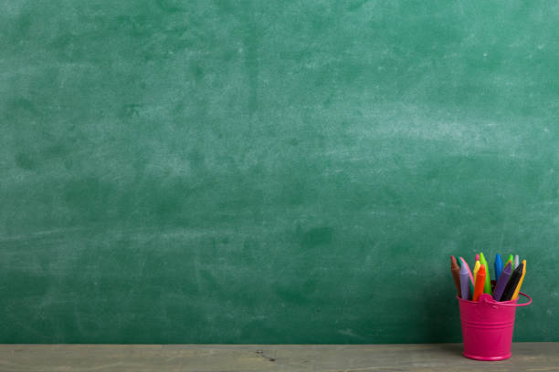 istock colored crayons and toy bear on the wooden table elementary school education concept, chalkboard background 2149349852