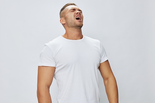 Man runny nose and cough, cold and flu, allergies, pain, in white t-shirt on white isolated background, copy space. High quality photo