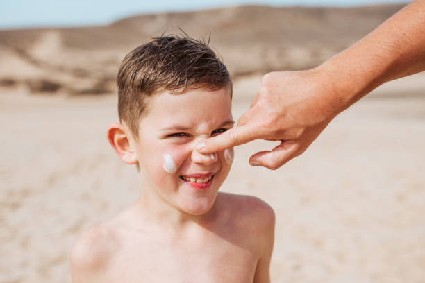 istock Boy with sunscreen lotion on face. Young boy si protected from sun with sunscreen. Concept of beach summer vacation with kids. 2149355434